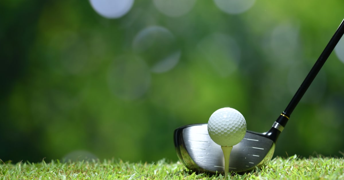 Golfball und Golf Driver auf Wiese