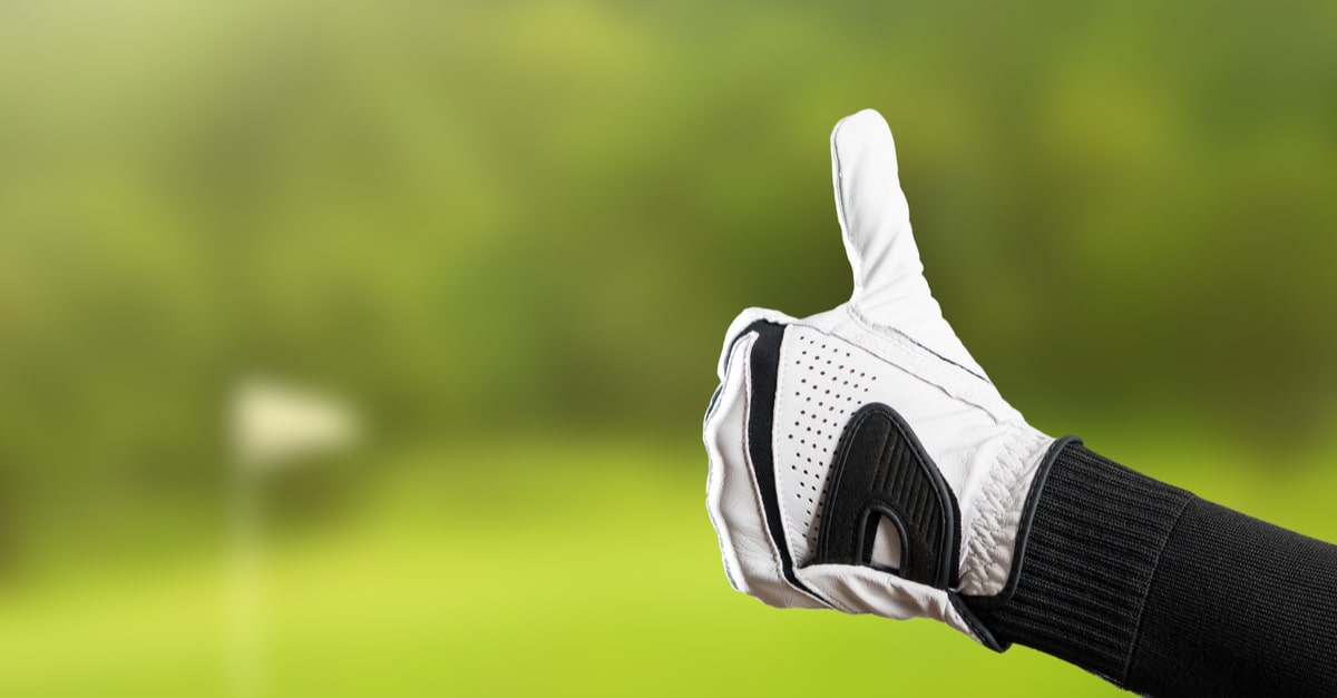 Golfer trägt Golfhandschuh & macht Daumen hoch Geste