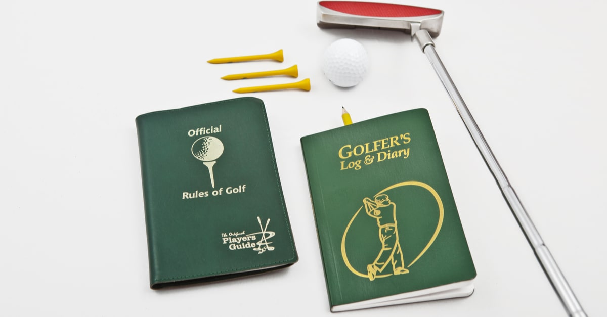Notizbuch und Golfregelbuch mit Golfequipment