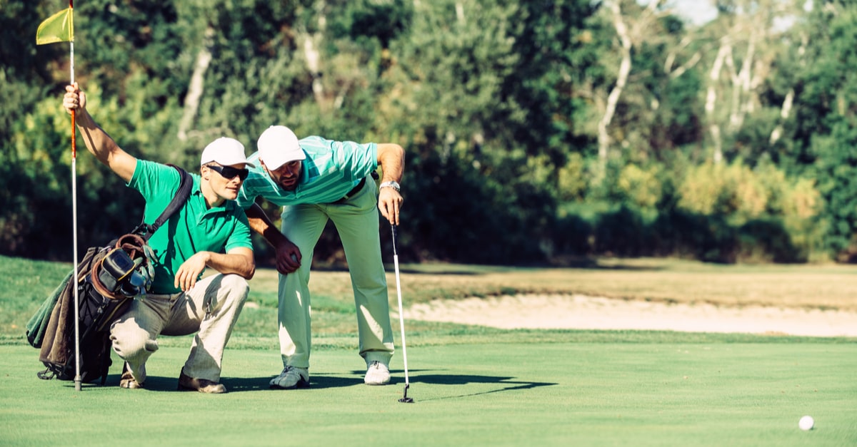 Golfer und Caddie unterhalten sich auf dem Grün
