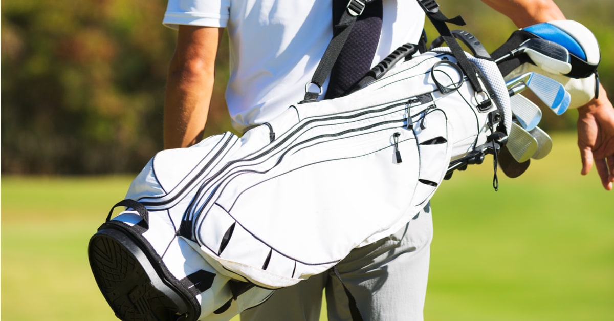 Ein Golfer, der ein Golfbag über seiner Schulter trägt.