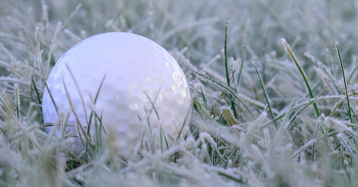 Ein weißer Golfball liegt im Schnee.